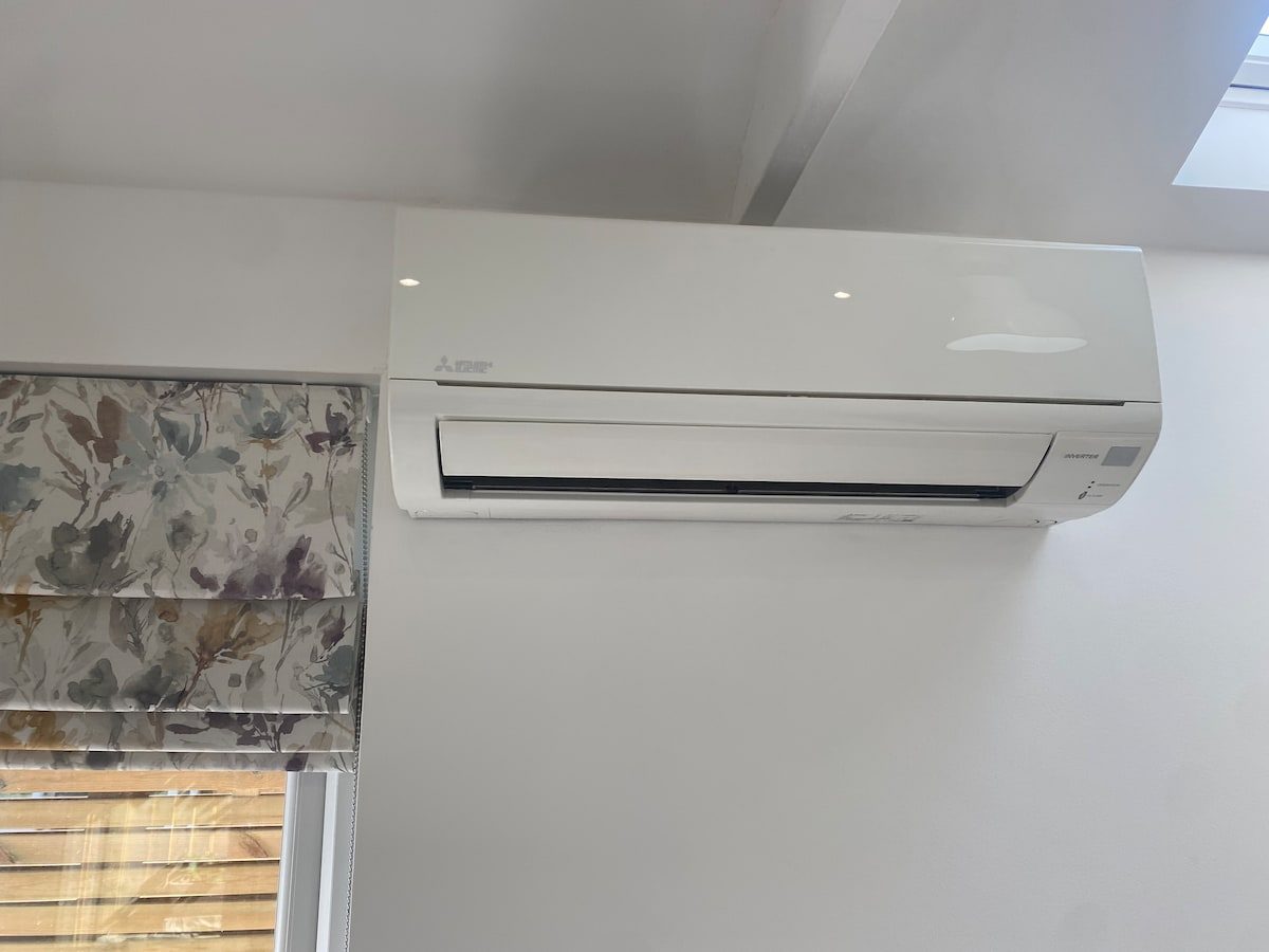 Wall-mounted air conditioning and heat pump unit above the window blind