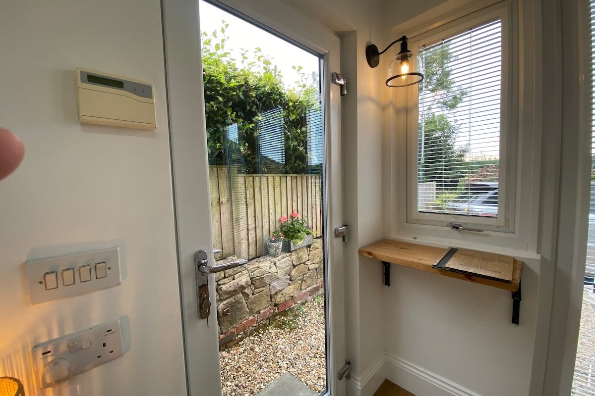 Entrance hallway with window, wall light and self check-in door