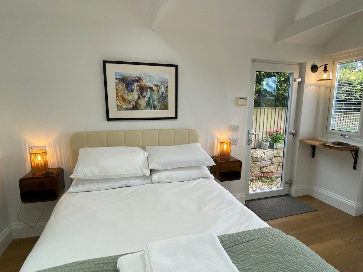 Double bed beside the bedside candles and artwork under a vaulted ceiling