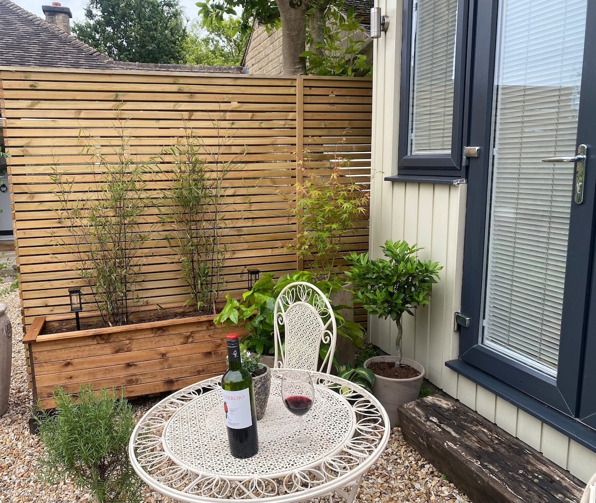 Outdoor seating area with planters, wine and glasses beside the cabin door