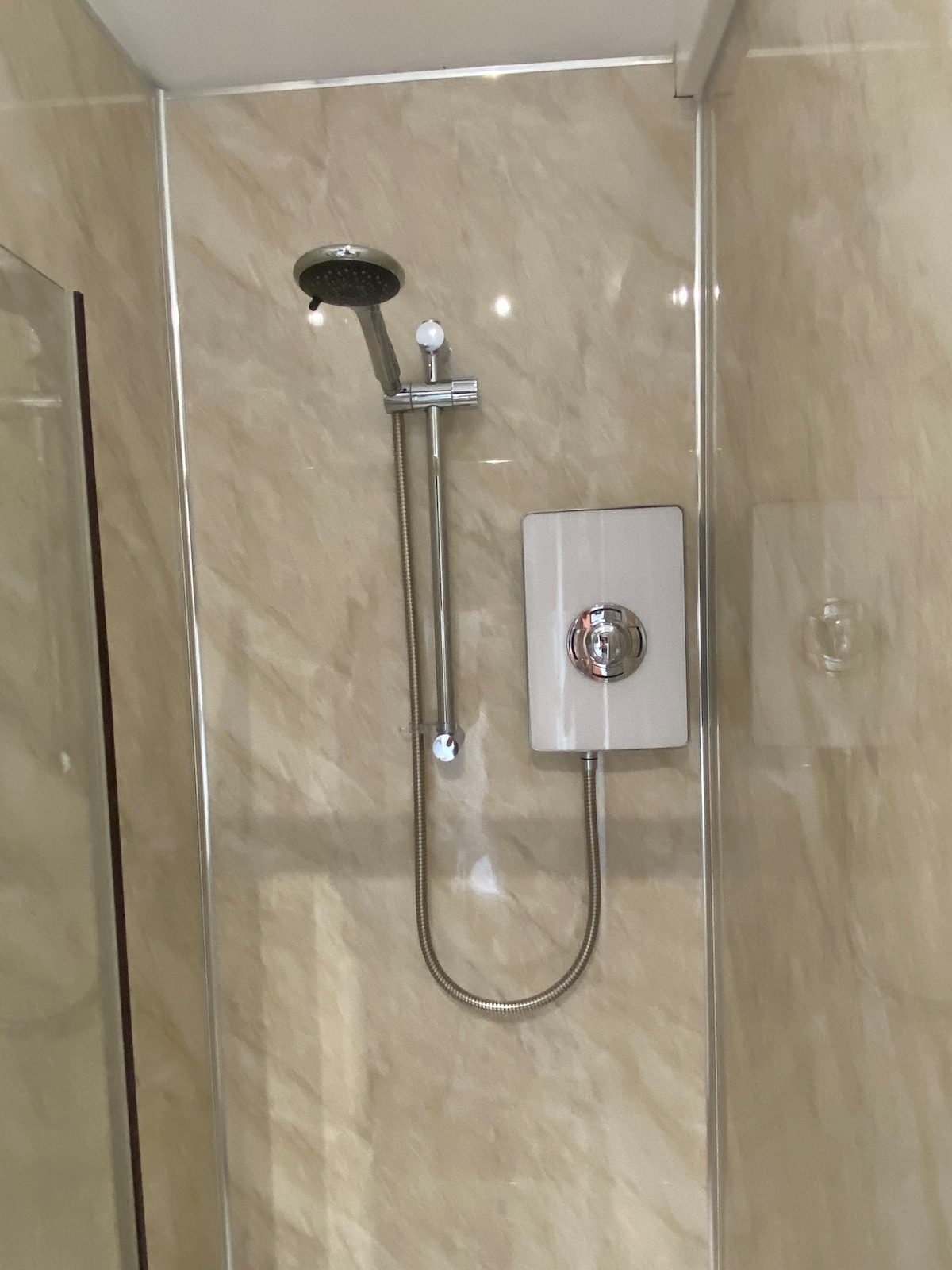 Rainfall shower head inside the tiled shower enclosure