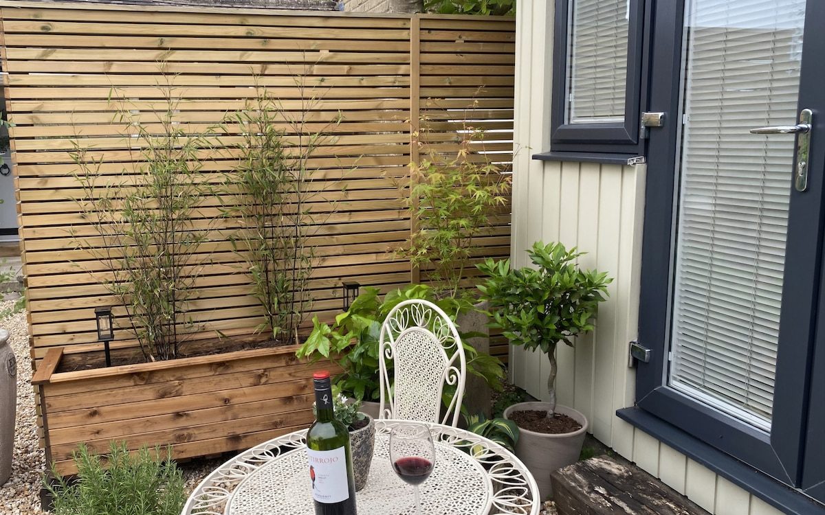Sheltered outdoor dining area screened by timber fencing and planters