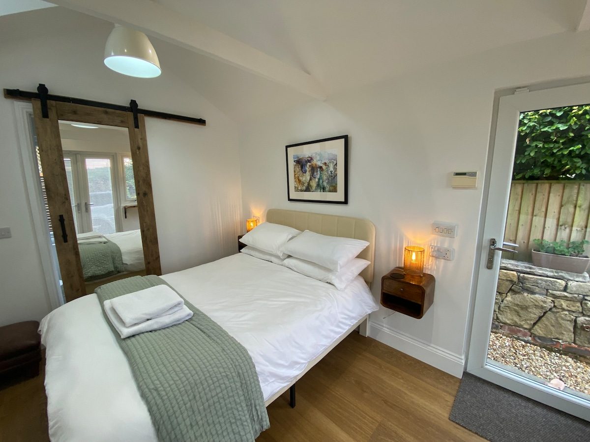 Double bed with crisp white linen, green throw and barn-style sliding door