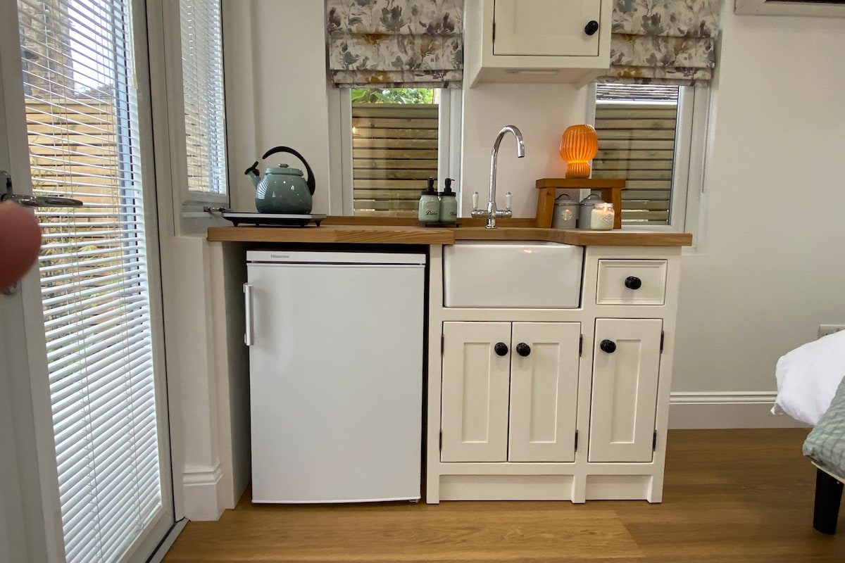 Kitchenette with fridge, kettle and crockery beside the window